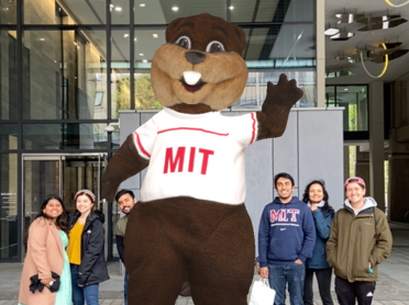 A group of people pose around a virtual copy of MIT's mascot Tim the Beaver.
